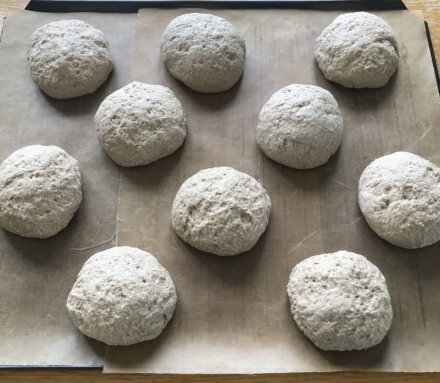 Photo looking down on a tray of 10 teff roll on a baking sheet ready to go in the oven to bake