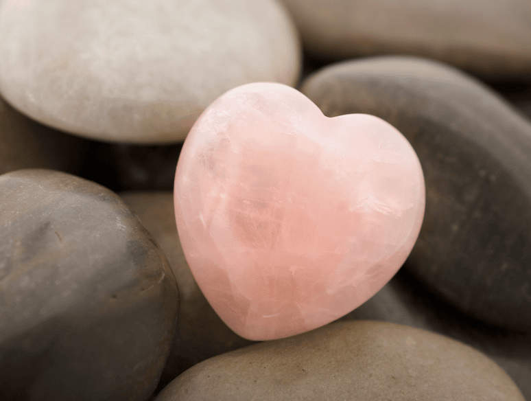 Rose Quartz heart on smooth stones representing The Blended approach for a holistic approach to wellness