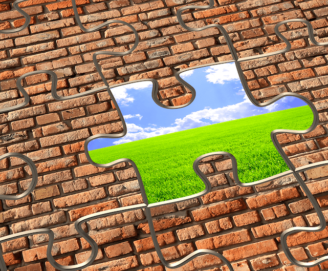 A jigsaw that is a brick wall with jigsaw shapes overlain. One piece has been removed to reveal blue sky, clouds and grass. This represents how we can help you to remove the blocks that are stopping you from seeing and experiencing better health and happiness. We help you to see the possibilities that lie beyond your current obstacles.