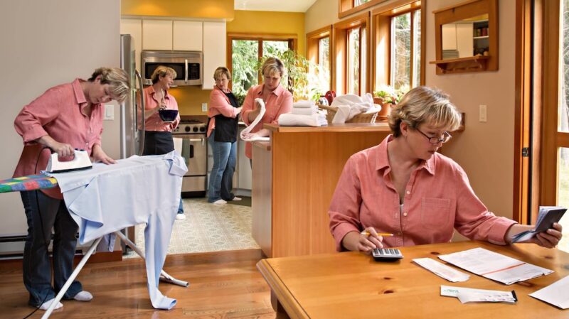 The perfect example of procratination a lady in the pink blouse is feature in this image several times she is ironing, cooking, doing paper work everything to avoid the task she is meant to be doing. It shoes how we can suddlenly find outselves doing menial tasks instead of the one we really really want to do.