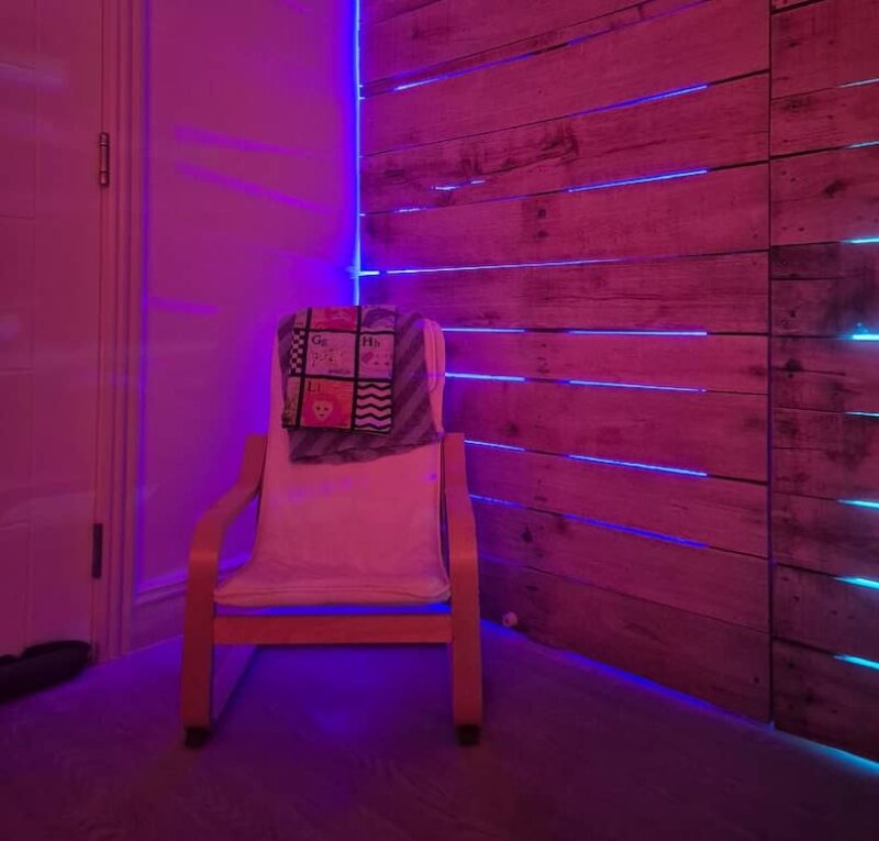 Chair in the Halo Breathing Space room with the purple glow of the salt therapy system illuminating the space and wooden panels behind